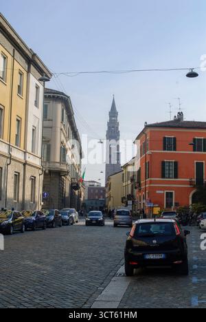 Cremona, Italie - 30 septembre 2025 Rue pavée historique à Crémone Italie avec Tall Bell Tower Landmark et bâtiments colorés sous une lumière Banque D'Images