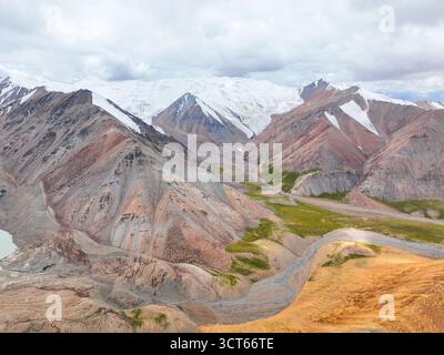 Vue aérienne large d'une immense chaîne de montagnes colorée avec des sommets enneigés, un glacier en recul et une vallée accidentée en contrebas Banque D'Images