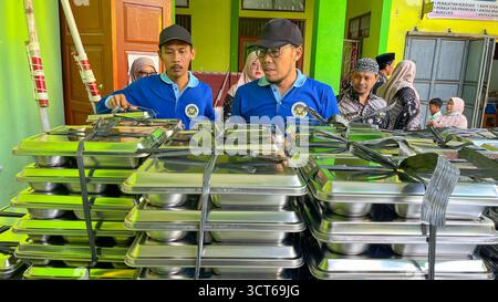 Klaten, Indonésie - le 25 septembre 2025, les agents de SPPG, les agents de déjeuner gratuits distribuent des conteneurs de nourriture Banque D'Images