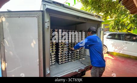 Klaten, Indonésie - le 25 septembre 2025, les agents de SPPG, les agents de déjeuner gratuits distribuent des conteneurs de nourriture Banque D'Images