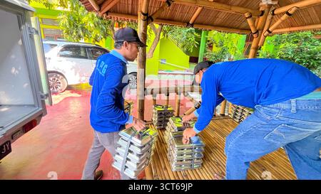 Klaten, Indonésie - le 25 septembre 2025, les agents de SPPG, les agents de déjeuner gratuits distribuent des conteneurs de nourriture Banque D'Images