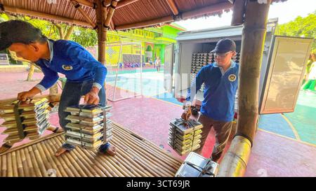 Klaten, Indonésie - le 25 septembre 2025, les agents de SPPG, les agents de déjeuner gratuits distribuent des conteneurs de nourriture Banque D'Images