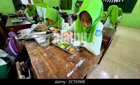 Klaten, Indonésie - le 25 septembre 2025 les élèves de madrasah tsanawiyah de niveau secondaire en Indonésie déjeunent dans la salle de classe pendant Banque D'Images