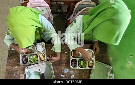 Klaten, Indonésie - le 25 septembre 2025 les élèves de madrasah tsanawiyah de niveau secondaire en Indonésie déjeunent dans la salle de classe pendant Banque D'Images