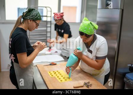 Piacenza, Italie - 25 septembre 2025 jeunes femmes fabriquant des pâtes Tortelli embrassant la tradition sécurité production alimentaire artisanale et entrepreneuriat régional Banque D'Images