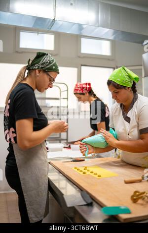 Piacenza, Italie - 25 septembre 2025 production artisanale de Tortelli dans une cuisine italienne professionnelle mettant en valeur le dévouement des jeunes femmes à la tradition Banque D'Images