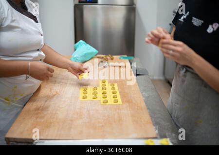Piacenza, Italie - 25 septembre 2025 jeunes femmes fabriquant des pâtes Tortelli traditionnelles embrassant la tradition artisanale de sécurité de la production alimentaire et l'autonomisation Banque D'Images