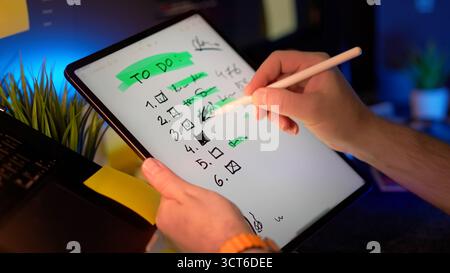 Tablette checklist notes numériques concept de planification de la productivité avec écriture manuelle et suppression des tâches à l'aide d'un stylet dans un espace de travail moderne Banque D'Images