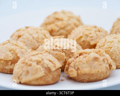 Pâtisseries dorées croustillantes au choux sur une assiette blanche, élégant dessert français servi lors d'un événement d'entreprise sur le toit à Paris. Banque D'Images