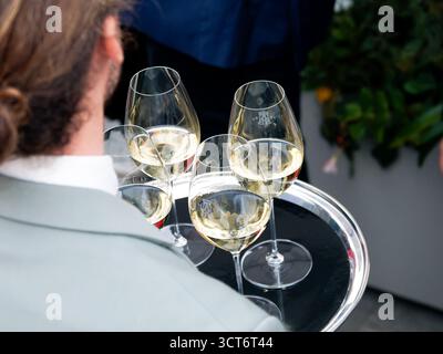 Verres de vin blanc sur un plateau argenté lors d’un événement corporatif sur le toit à Paris, ambiance élégante et conviviale en soirée. Banque D'Images