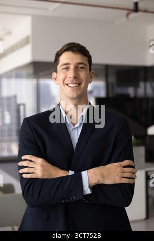 Heureux jeune homme d'affaires hispanique prospère posant au bureau Banque D'Images