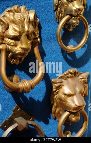 Frappeur de porte en laiton orné en forme de visage de Lions sur une porte verte, Rome, Italie. Banque D'Images