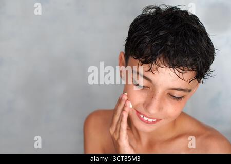 Routines d'auto-soin pour la peau. Adolescent appliquant un hydratant pour réguler l'acné. Banque D'Images