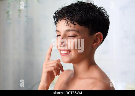 routine de soins de la peau et soins de la peau pour les enfants et les adolescents. garçon de preteen appliquant de la crème sur son visage Banque D'Images