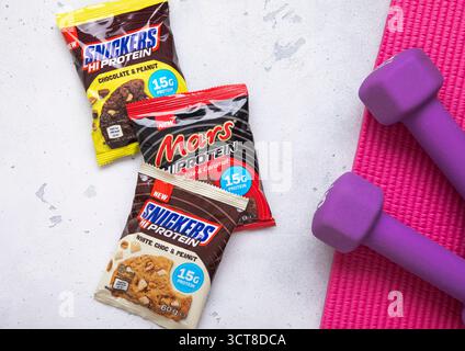 LONDRES, Royaume-Uni - 27 JUIN 2025 : biscuits Snickers et mars Protein Bar sur fond de salle de gym. Banque D'Images