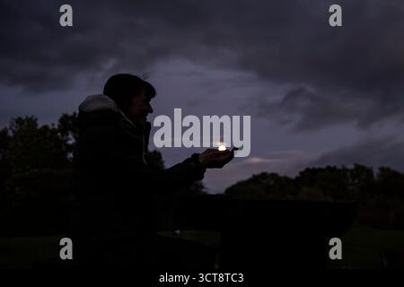 Vue latérale de la silhouette d'une femme au clair de lune avec les mains bombées tenant la lune. Banque D'Images