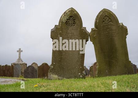 Pierres tombales recouvertes de mousse dans le cimetière de l'île de Man avec des détails décoratifs sculptés Banque D'Images