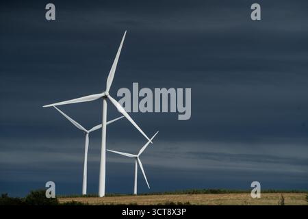 Éoliennes blanches contre le ciel orageux dramatique dans la campagne rurale Banque D'Images