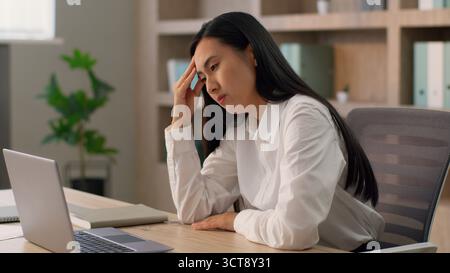Fatigué bouleversé asiatique employé de bureau japonais employeur femme d'affaires chinoise coréenne femme d'affaires entrepreneur ferme ordinateur portable de bureau fin Banque D'Images