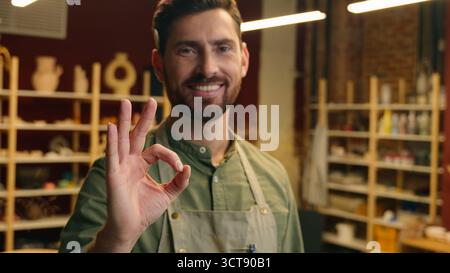 Heureux souriant joyeux homme de gars caucasien homme d'affaires homme de petite entreprise propriétaire masculin dans le potier vendeur de tablier regardant le sourire de la caméra montrant le signe OK OK OK Banque D'Images