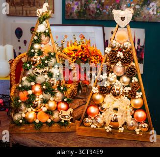 Décor festif de vacances ! Ces arbres de Noël en bois faits à la main sont ornés d'ornements, de pommes de pin et de lumières pour un charme unique et rustique. Banque D'Images