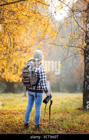 Photographe avec appareil photo explorant la forêt d'automne. Femme est à la recherche d'aventure en plein air en saison d'automne Banque D'Images