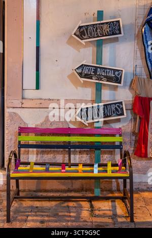Un banc vibrant et multicolore se trouve en face d'un bâtiment avec un panneau qui indique « Joycepapas » à bo. Centre historique de Queretaro, architecte colonial Banque D'Images