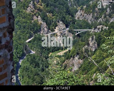 Vue depuis la forteresse de Poenari sur un pont et une route sinueuse dans la vallée de Argeș, en Roumanie, avec des falaises boisées et des paysages spectaculaires de montagne des Carpates Banque D'Images
