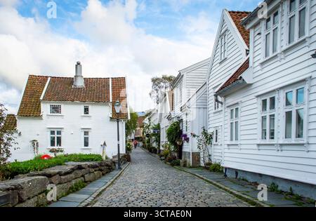 Stavanger, Sep. 4, 2025. Vue sur le quartier historique de Gamle Stavanger Norvège avec des maisons en bois blanc et rue pavée couverte après le coucher du soleil. Banque D'Images