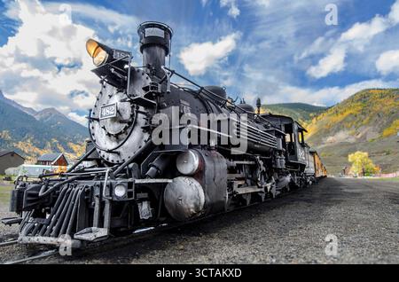 Locomotive à vapeur noire historique sur rails dans le paysage d'automne de la ville de montagne sous le ciel bleu Banque D'Images