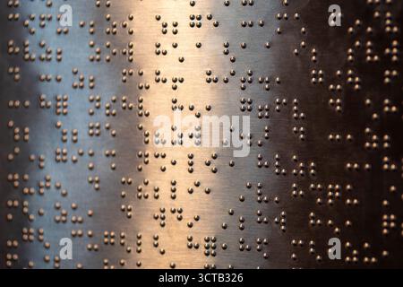 Le braille est un système d’écriture tactile pour les malvoyants, vital pour leur accès à l’information et leur intégration sociale. Banque D'Images