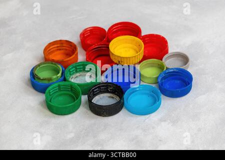 De nombreux bouchons de bouteilles en plastique colorés et assortis dispersés sur un sol en carreaux blancs. Gros plan pour le recyclage, l'upcycling, l'artisanat de bricolage créatif, les projets de réutilisation, un Banque D'Images