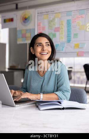 Heureuse belle jeune femme d'affaires latine travaillant dans le bureau Banque D'Images