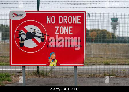 Bruxelles, Belgique - 5 octobre 2025 : gros plan d'un panneau d'avertissement rouge vif No Drone zone à l'aéroport de Bruxelles, placé contre la clôture du périmètre avec le Banque D'Images