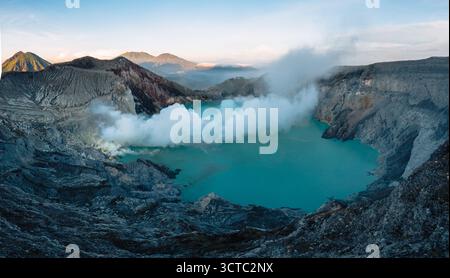 Vue aérienne du magnifique lac de cratère turquoise niché dans le paysage accidenté et volcanique, enveloppé dans la brume éthérée et la douce lueur du ri Banque D'Images