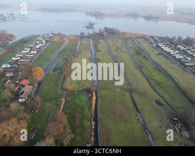 Vue aérienne des canaux coupant à travers les prairies verdoyantes, reflétant la douce lumière du matin entre les rangées de maisons pittoresques, Giethoorn, Overijssel, N. Banque D'Images