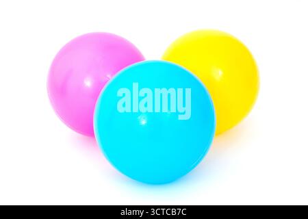 Trois balles de jeu en plastique bleu, jaune et rose sur fond blanc Banque D'Images