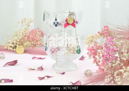 Concept baroque avec bijoux en lunettes, boucles d'oreilles, collier, perles, fausse montre décorée avec le souffle de bébé, plumes et pétales de rose. Banque D'Images