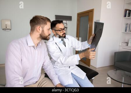 Le médecin et le patient s'engagent dans une discussion diagnostique lors de l'examen des radiographies Banque D'Images