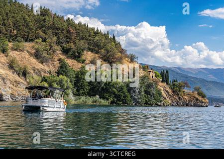 Bateau d'excursion sur le lac Ohrid près de l'église de préparés John à Kaneo à Ohrid, Macédoine du Nord, paysage d'été pittoresque avec des montagnes et de l'eau bleue. Banque D'Images