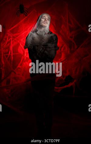 Homme horrible avec le maquillage zombie dans une toile d'araignée sur un fond rouge sanglant. copier l'espace Banque D'Images