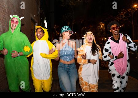 Groupe multiethnique de jeunes amis s'amusant sur les tronçons dans la nuit - des gens multiraciaux cool élégants portant des costumes drôles élégants traînant Banque D'Images