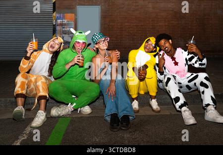 Groupe multiethnique de jeunes amis s'amusant sur les tronçons dans la nuit - des gens multiraciaux cool élégants portant des costumes drôles élégants traînant Banque D'Images
