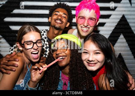 Groupe multiethnique de jeunes amis s'amusant sur les étirements dans la nuit - des gens multiraciaux cool élégants portant des vêtements élégants traînant befor Banque D'Images