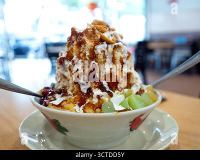 Dessert glacé rasé appelé Ice Kacang ou ais kacang en Malaisie avec des ingrédients de mélange d'arachides, haricots rouges, lait, sirop rouge et gelée douce colorée. Banque D'Images