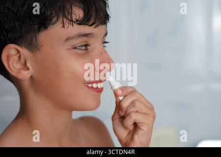 adolescence et soins de la peau. Adolescent appliquant un traitement à sa lèvre supérieure. Banque D'Images