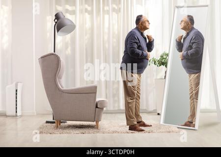 Plan de profil pleine longueur d'un homme mature se préparant devant un miroir Banque D'Images
