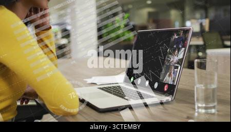 Femme d'affaires penchée en pull jaune engageant la réunion virtuelle au bureau, avec ordinateur portable, espace de copie Banque D'Images