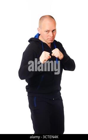 Homme en survêtement noir avec détails bleus debout dans la position de combat prêt à la boîte Banque D'Images