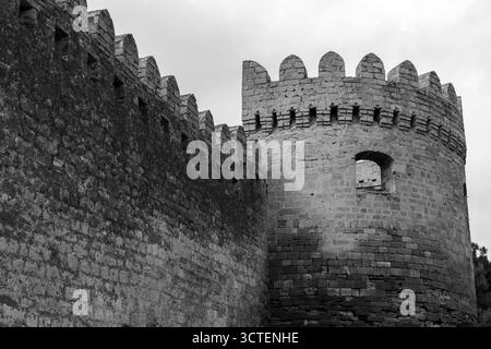 Image en noir et blanc d'une forteresse médiévale avec un haut mur de pierre et une tour arrondie avec des créneaux crénelés. Bakou, Azerbaïdjan Banque D'Images